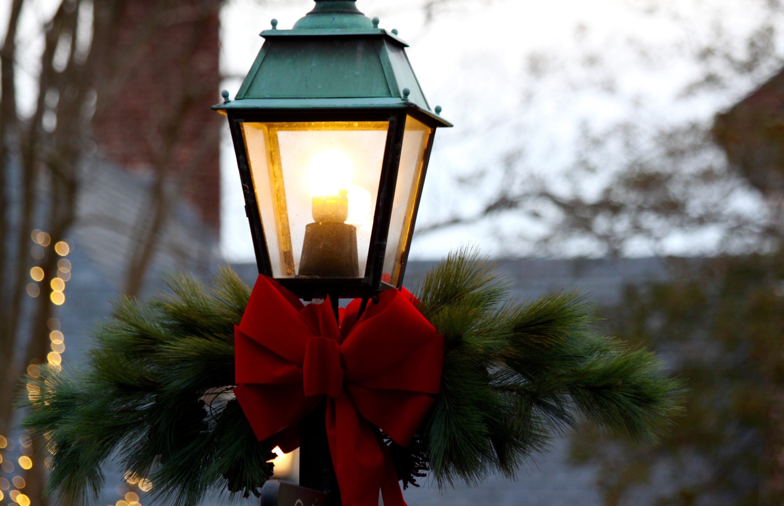 Lamp post with evergreen garland and red Holiday Bow