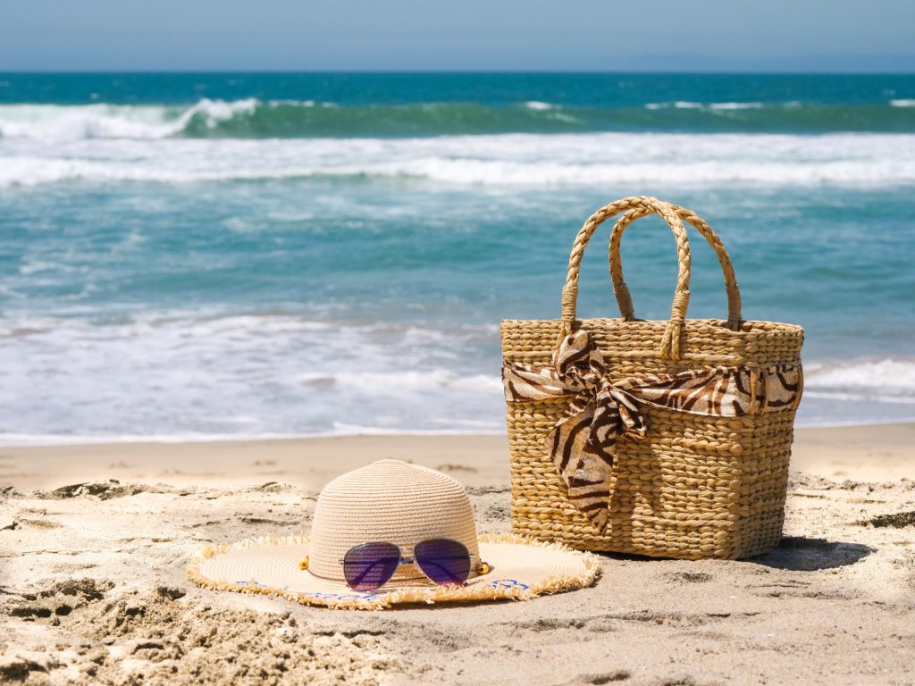 beach bag and sun hat on sand