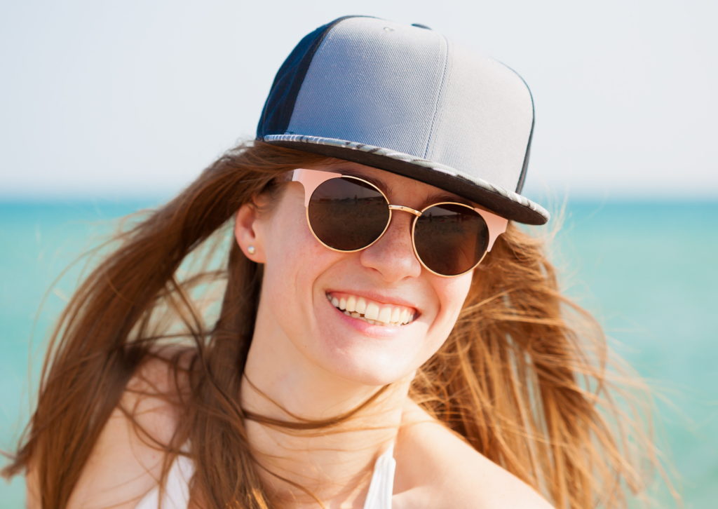 Woman at beach wearing hat and sunglasses